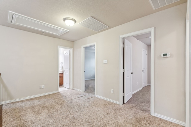unfurnished bedroom featuring carpet floors, baseboards, visible vents, and attic access