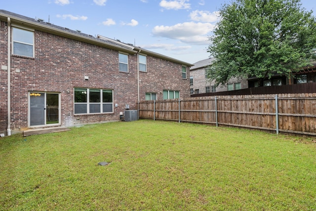 back of property featuring a yard, brick siding, cooling unit, and a fenced backyard