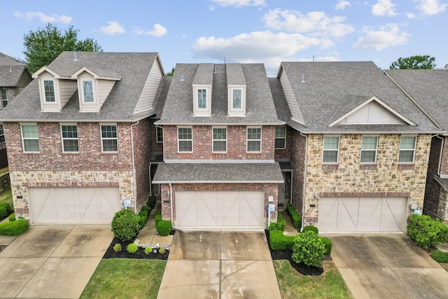multi unit property with an attached garage, roof with shingles, driveway, and brick siding