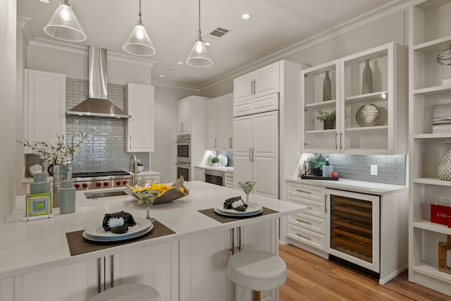 2800 Lakeside Pkwy Unit 1003, Flower Mound, TX 75022 - kitchen featuring wall chimney range hood, stainless steel double oven, tasteful backsplash, beverage cooler, and a breakfast bar