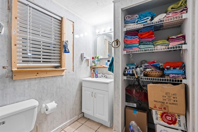 bathroom featuring tile patterned flooring, vanity, toilet, baseboards, and a textured ceiling