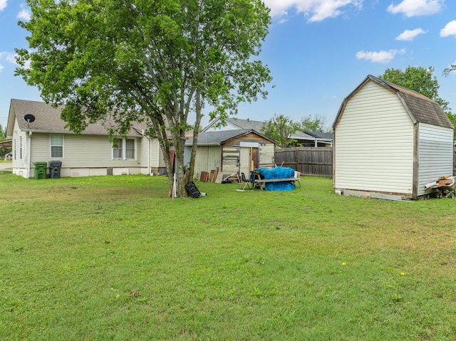 view of yard featuring fence, a storage unit, and an outdoor structure