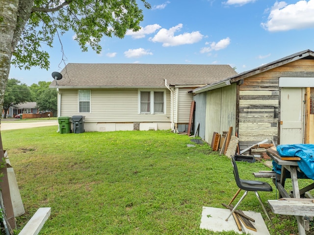 rear view of property with a lawn and a shingled roof