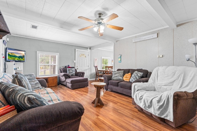 living room featuring a ceiling fan, visible vents, beam ceiling, and light wood-style floors