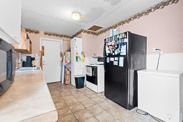 kitchen with freestanding refrigerator, fridge, white range with electric cooktop, light countertops, and a sink