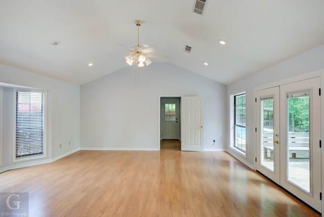 unfurnished room with light wood-style floors, a wealth of natural light, lofted ceiling, and visible vents