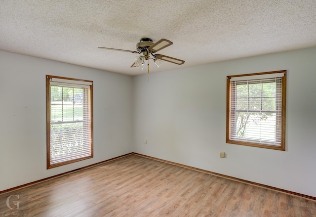 empty room with a textured ceiling, ceiling fan, wood finished floors, and a healthy amount of sunlight