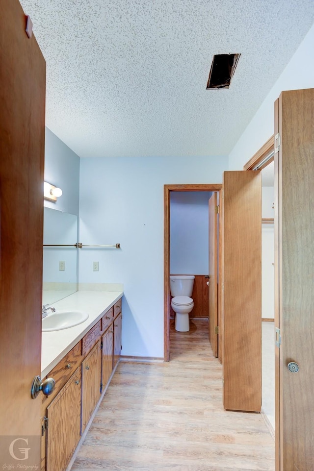 bathroom featuring toilet, a textured ceiling, wood finished floors, and vanity