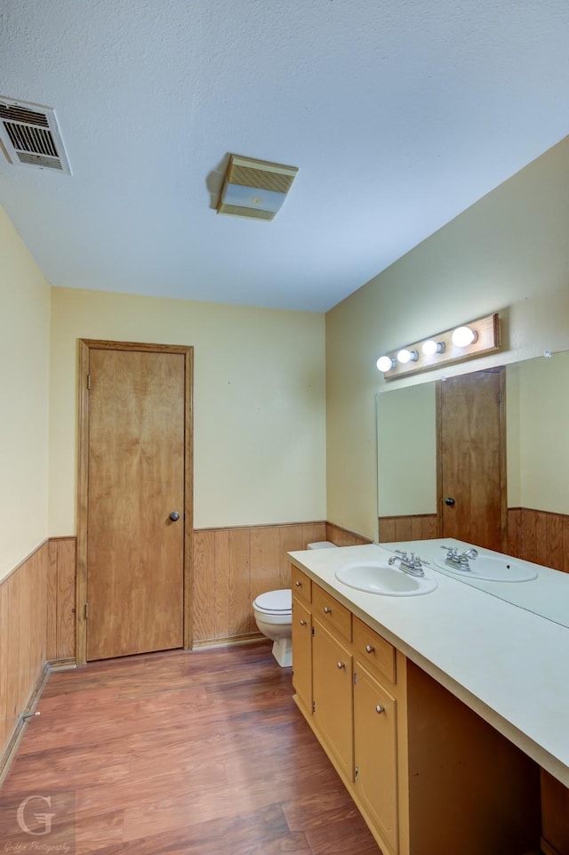 bathroom featuring visible vents, a wainscoted wall, wooden walls, and wood finished floors
