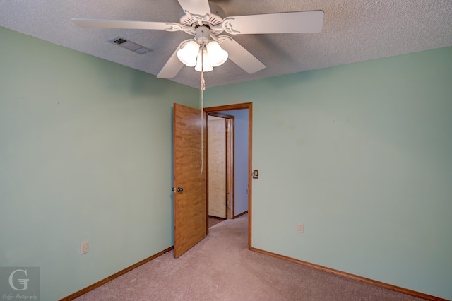 spare room featuring baseboards, ceiling fan, light colored carpet, and visible vents