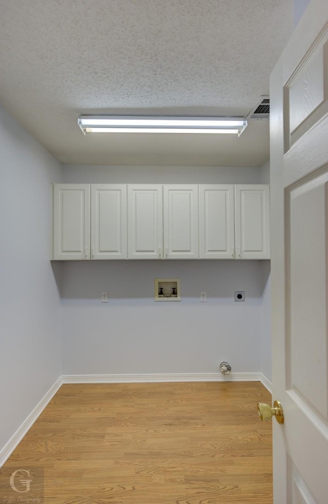 laundry area with cabinet space, washer hookup, a textured ceiling, gas dryer hookup, and hookup for an electric dryer