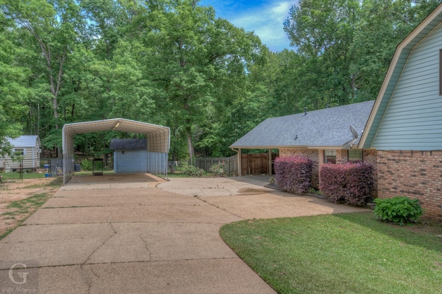 view of yard with fence, an outdoor structure, a storage shed, concrete driveway, and a carport