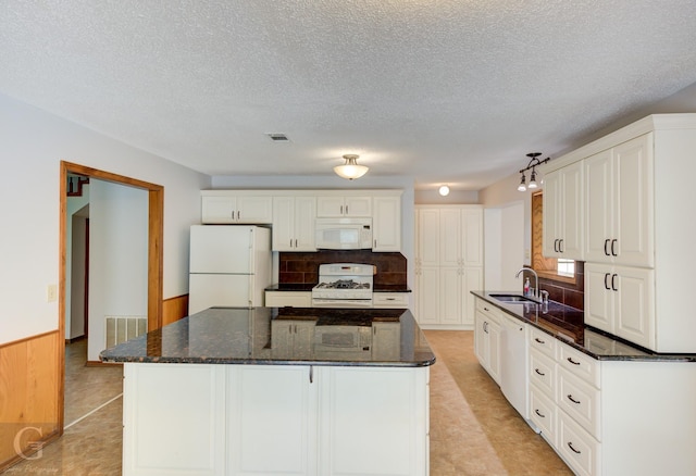 kitchen with a center island, a sink, white cabinets, and white appliances