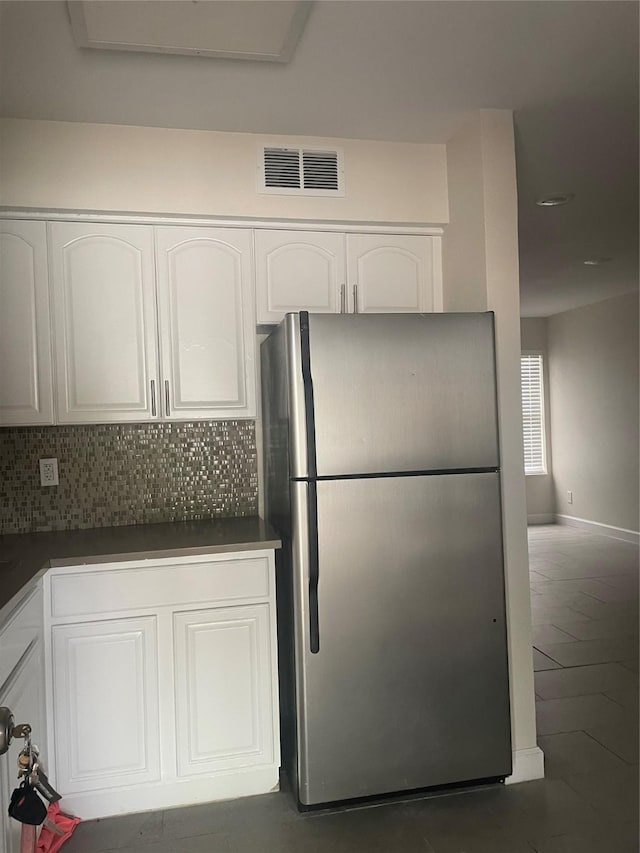 7030 Fair Oaks Ave Unit 111, Dallas, TX 75231 - kitchen featuring visible vents, freestanding refrigerator, dark countertops, white cabinets, and backsplash