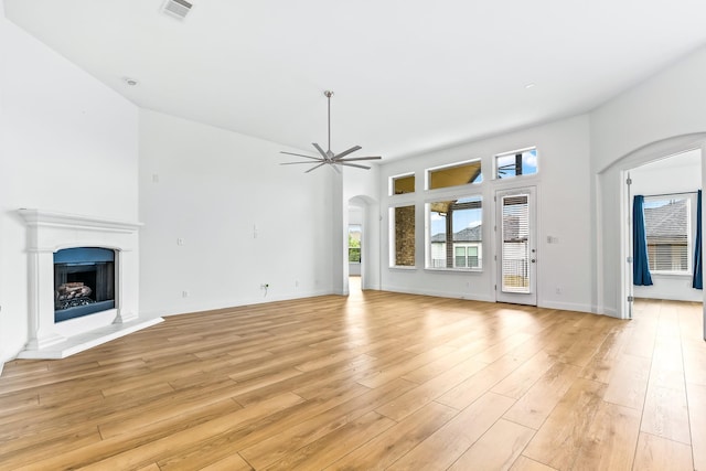 2407 Resort Dr, Heath, TX 75126 - unfurnished living room with ceiling fan, arched walkways, a fireplace with raised hearth, light wood-style flooring, and visible vents