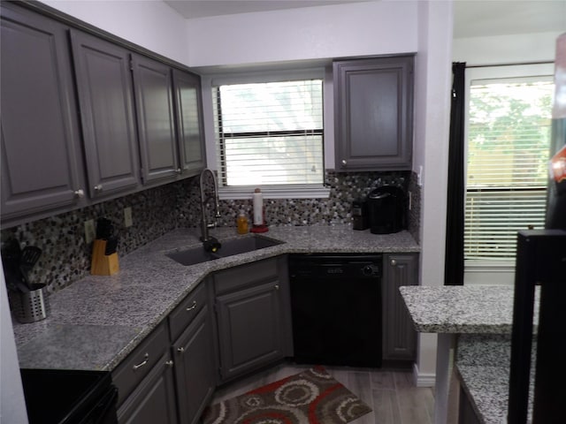 kitchen with backsplash, a sink, gray cabinetry, black appliances, and light wood-style floors