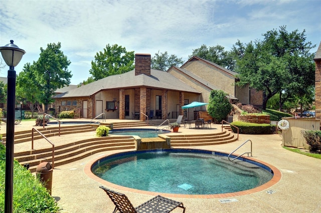 pool with a hot tub and a patio