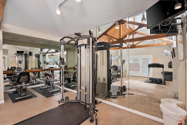 exercise room with track lighting, a textured ceiling, and lofted ceiling