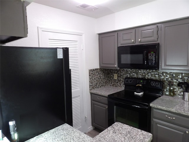 kitchen featuring backsplash, visible vents, gray cabinets, and black appliances