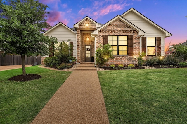ranch-style house with a yard, brick siding, and fence