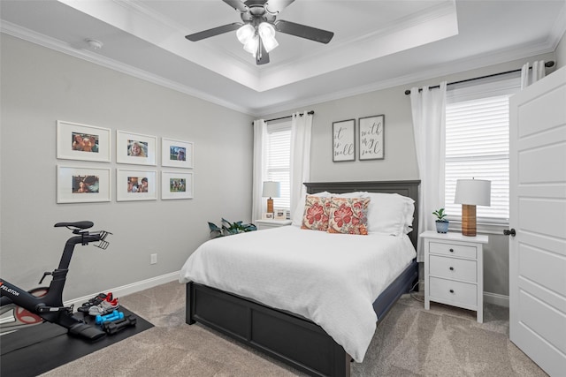 carpeted bedroom featuring crown molding, baseboards, ceiling fan, and a raised ceiling