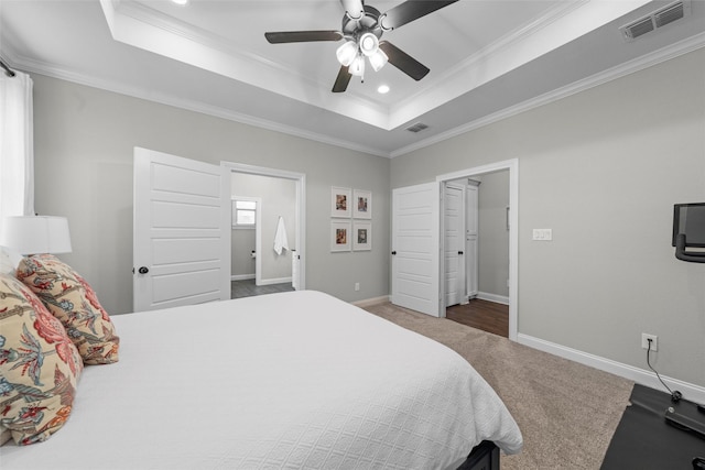 carpeted bedroom featuring baseboards, ornamental molding, a tray ceiling, and visible vents