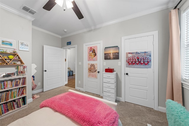 carpeted bedroom featuring crown molding, baseboards, a ceiling fan, and visible vents