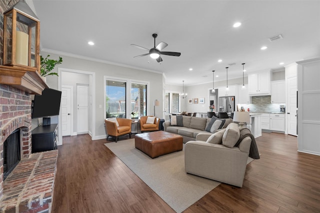 living area with ceiling fan, a brick fireplace, recessed lighting, visible vents, and ornamental molding