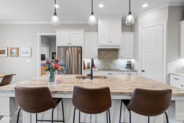 kitchen with a sink, stainless steel fridge with ice dispenser, crown molding, and backsplash
