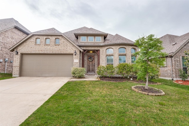 french country style house featuring driveway, roof with shingles, a front yard, a garage, and brick siding
