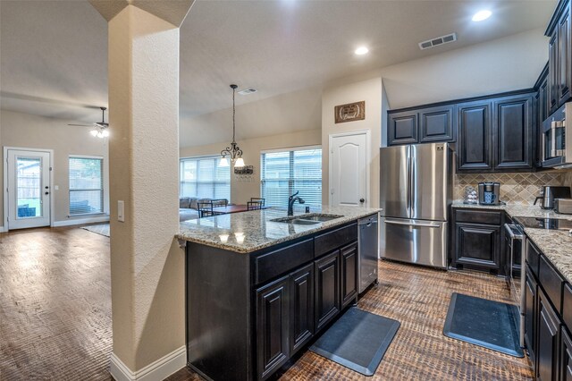 kitchen with a sink, decorative backsplash, appliances with stainless steel finishes, and light stone countertops