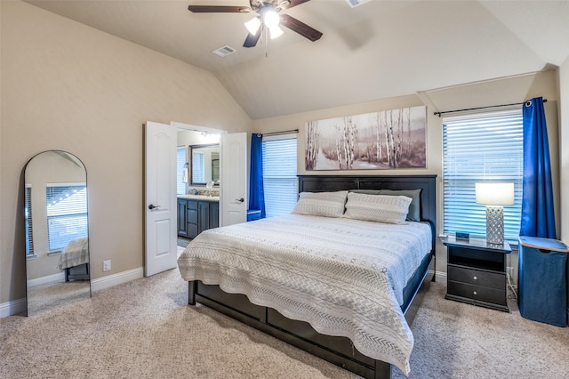 carpeted bedroom featuring visible vents, lofted ceiling, baseboards, ceiling fan, and ensuite bath