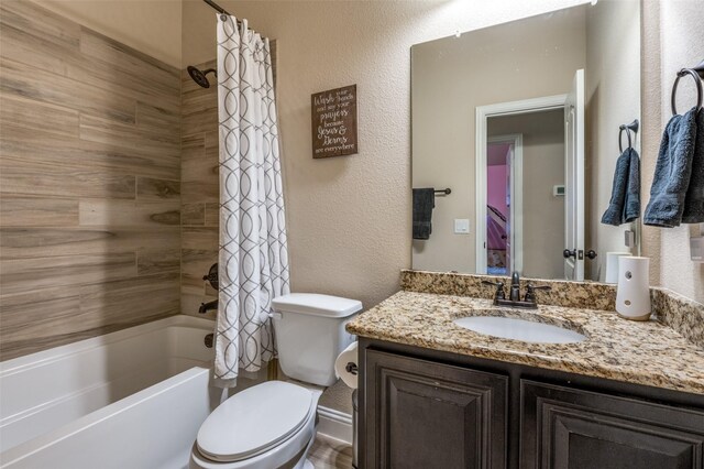 bathroom with vanity, a textured wall, toilet, and shower / tub combo