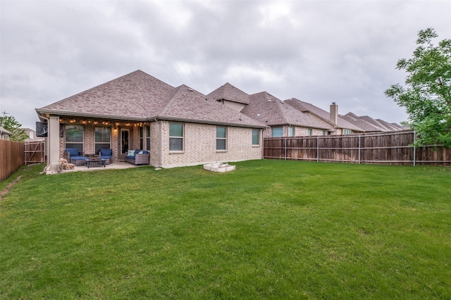 rear view of property featuring a yard, brick siding, a patio, and a fenced backyard