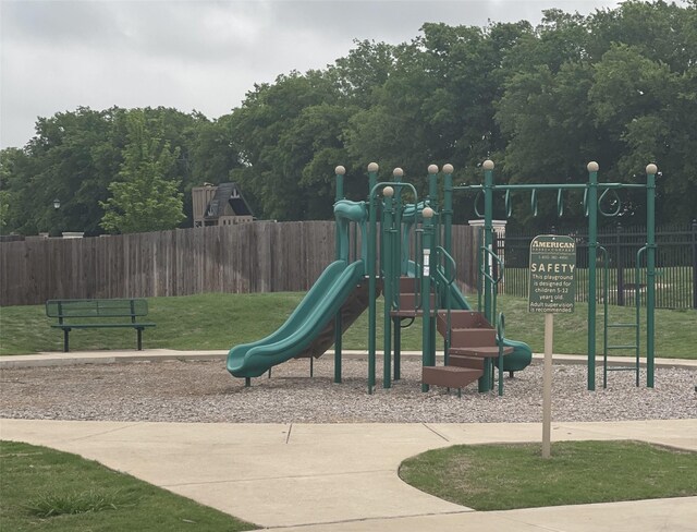 community jungle gym featuring fence and a lawn
