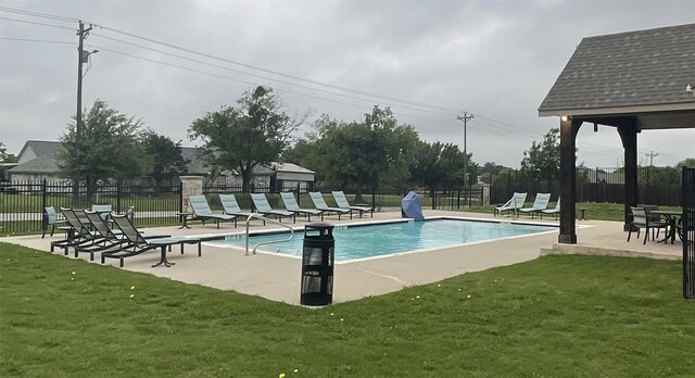 community pool featuring a yard, a patio, and fence