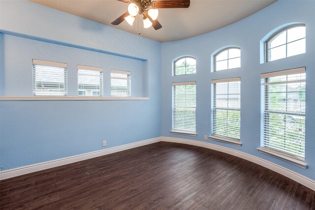 spare room featuring a ceiling fan, baseboards, and dark wood-style floors