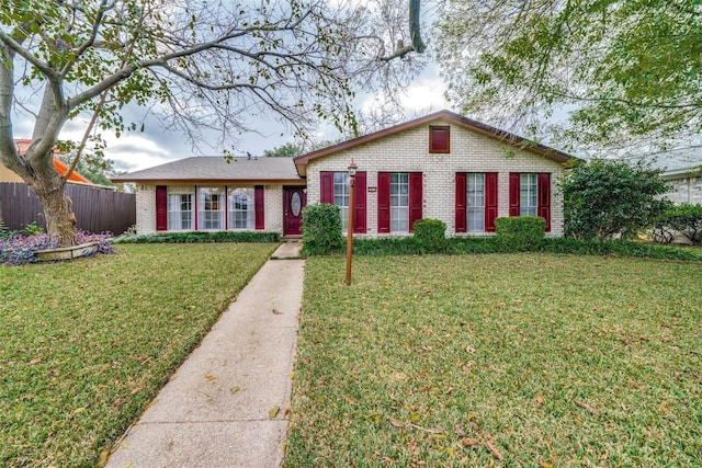 view of front of house featuring fence, a front yard, and brick siding