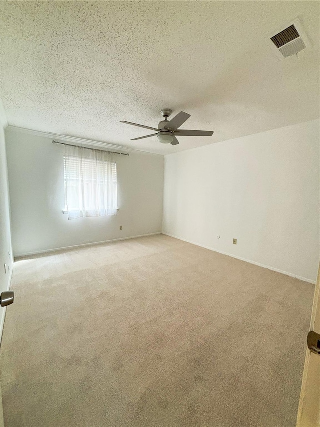 unfurnished room featuring a ceiling fan, light colored carpet, visible vents, and a textured ceiling