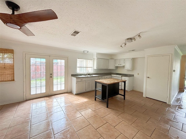 kitchen with visible vents, ceiling fan, a textured ceiling, french doors, and range