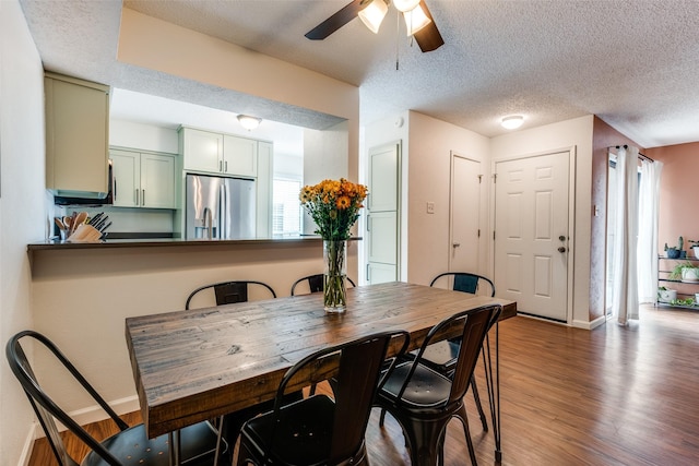 dining space featuring a ceiling fan, baseboards, wood finished floors, and a textured ceiling