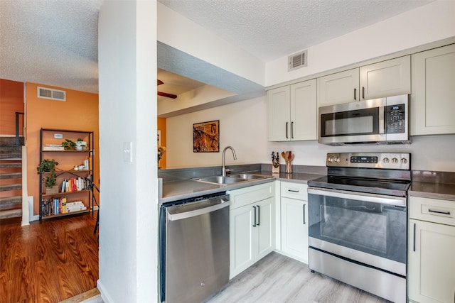 kitchen with visible vents, a sink, a textured ceiling, and stainless steel appliances