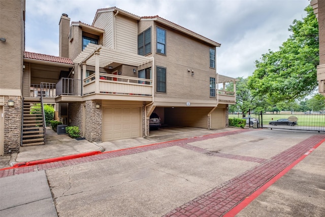 exterior space with fence, a garage, stucco siding, stairway, and a balcony