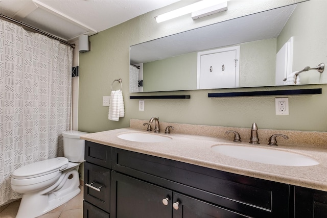 bathroom featuring double vanity, toilet, tile patterned floors, and a sink