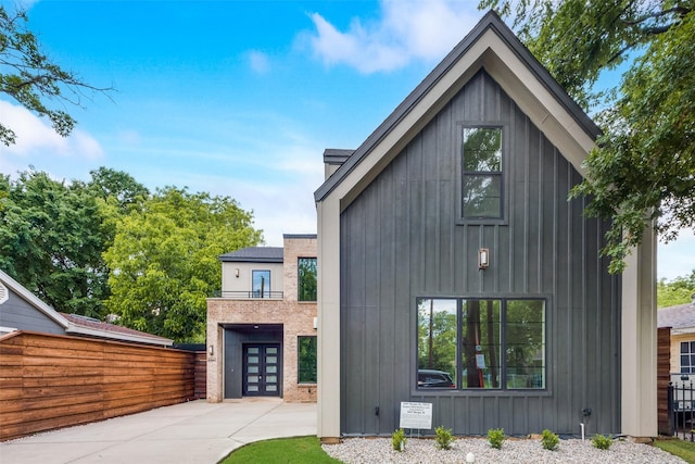 view of front facade featuring board and batten siding, fence, and french doors