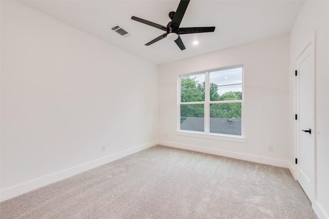 spare room featuring a ceiling fan, baseboards, light colored carpet, and visible vents