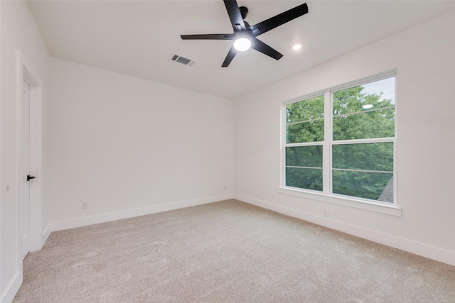 spare room with visible vents, baseboards, ceiling fan, and light colored carpet