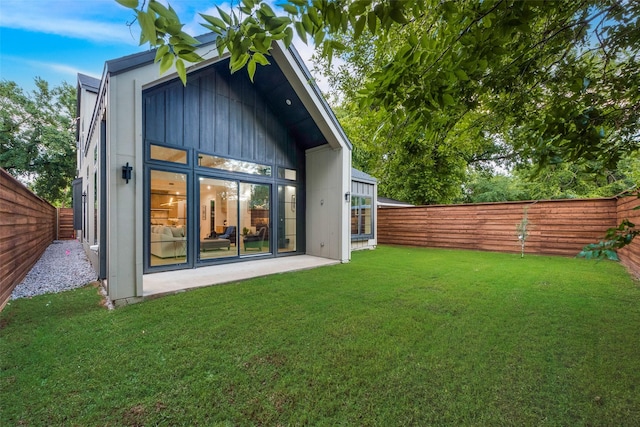 rear view of house with a yard, a fenced backyard, and a patio area