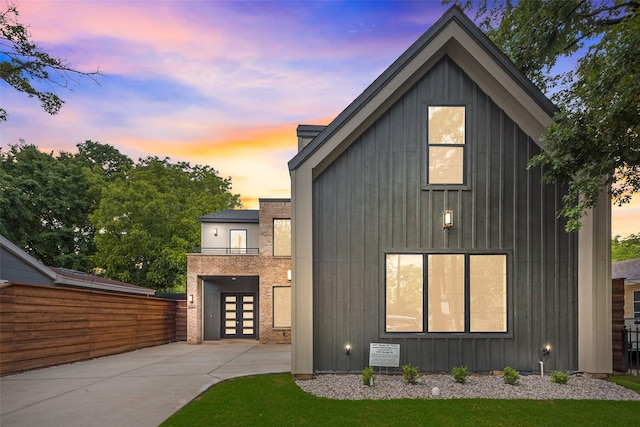 view of front facade with board and batten siding, fence, driveway, and french doors