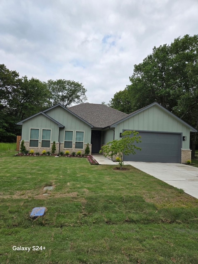 ranch-style house with a front yard, a shingled roof, board and batten siding, concrete driveway, and an attached garage